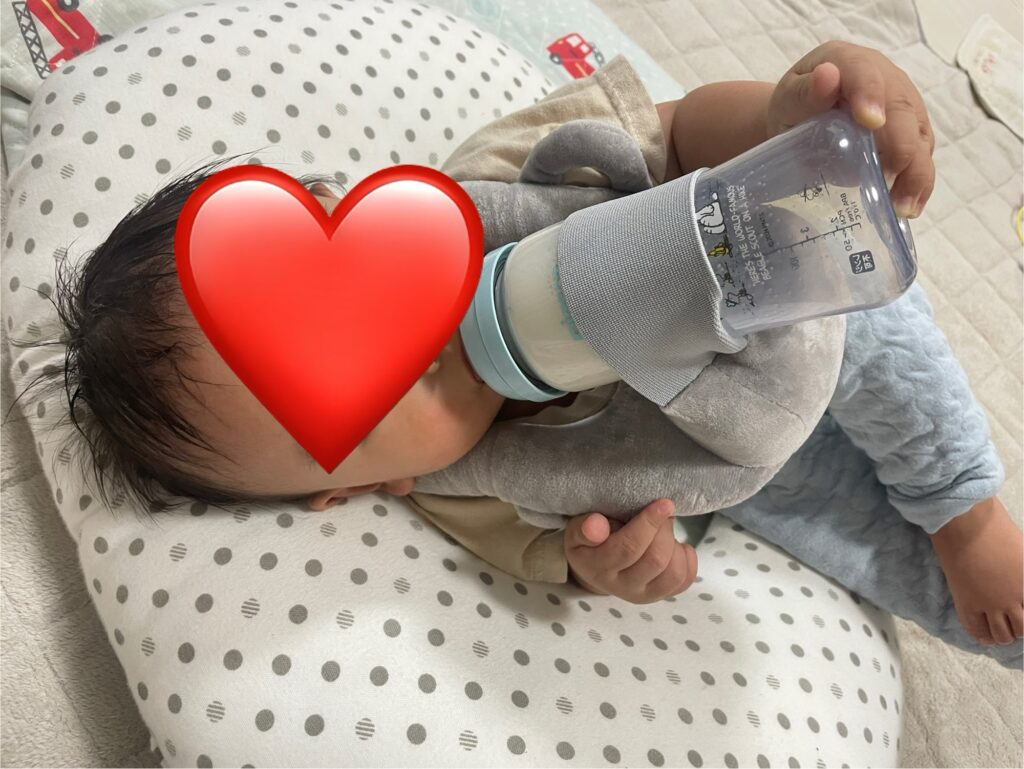 授乳クッションの上でCocoPon 哺乳瓶ホルダーを使っている様子。赤ちゃんがリラックスしてミルクを飲んでいる。